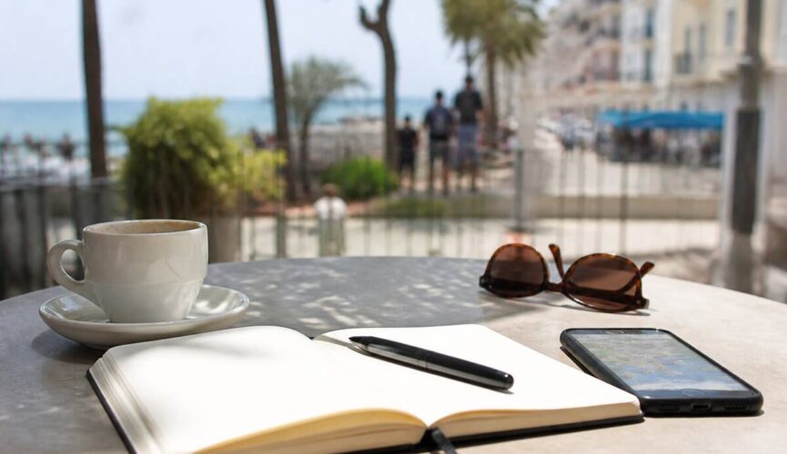 Notitieboek en reisbenodigdheden op tafel tijdens het plannen van een vakantie