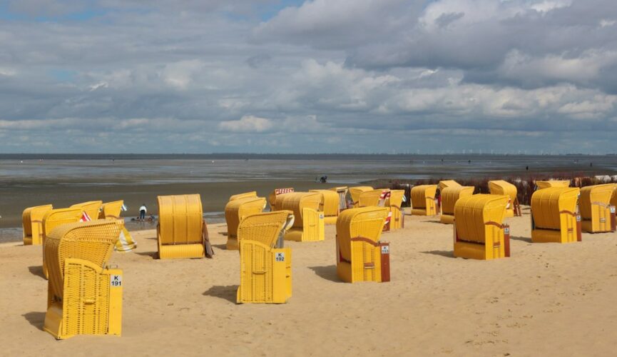 yellow plastic trash bins on brown sand under white clouds during daytime